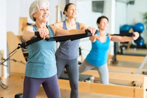 Toning Arms After 60: Empowering Womens Fitness Through Effective Weight Training 2 older woman doing weight training Trowbridge and resistance in the gym to tone upper arms